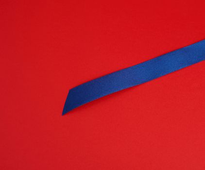 dark blue silk shiny ribbon on a red background, festive design element, close up