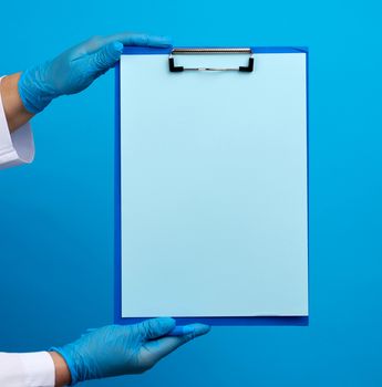 female doctor's hands in blue medical latex gloves holds a folder with a paper clip, place for writing a diagnosis, message