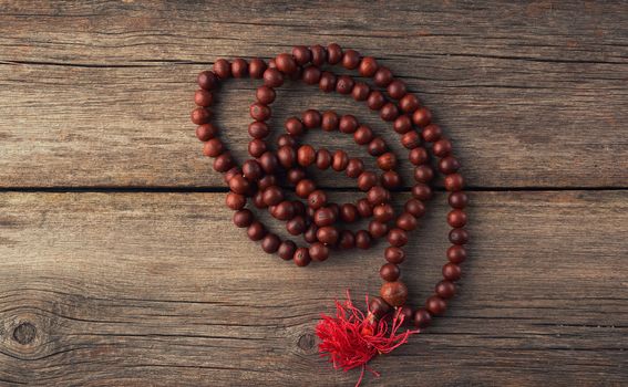 brown wooden prayer rosary on a wooden background from gray old planks, top view