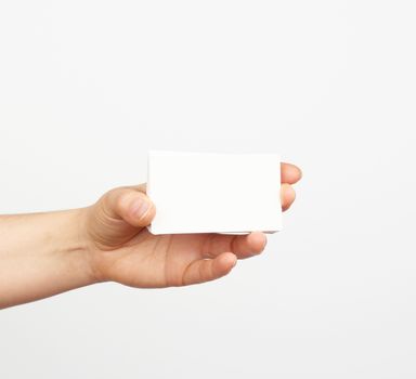 female hand holds a stack of white rectangular paper business cards on a white background, identity concept