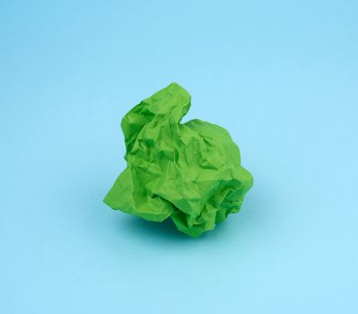 crumpled sheet of green paper on a blue background, close up