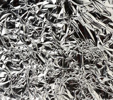 texture of shiny crumpled piece of gray foil, packaging material for food and objects, full frame