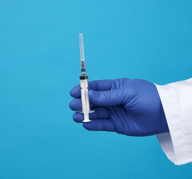 male doctor in white coat, blue latex medical gloves holding a plastic syringe, concept of timely vaccination