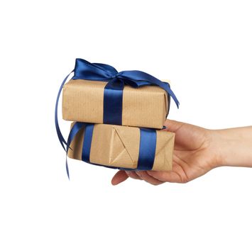 hand holds a stack of wrapped gifts in brown craft paper with tied silk bows, subject is isolated on a white background