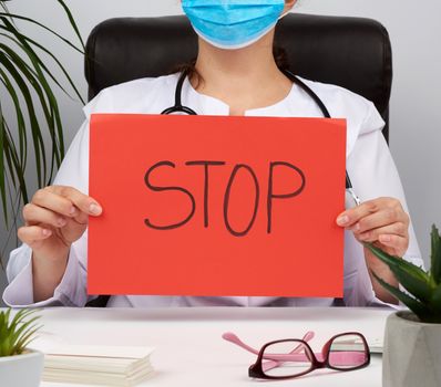 medic is sitting in a brown leather chair in the office holding a red sheet of paper with the words stop, concept is not to panic, keep calm