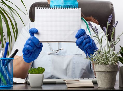 medic woman in white coat, blue latex gloves holding an open notebook with blank white sheets, white background, place for text