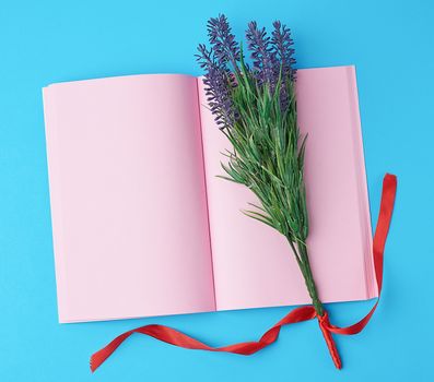 open notebook with blank pink pages, bouquet of lavenders on a blue background, top view, flat lay