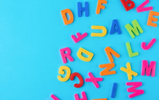 plastic multi-colored letters of the English alphabet on a blue background, top view, back to school, copy space