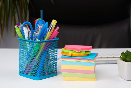 stationery in a blue metal stand stand on a white table, workplace, close up