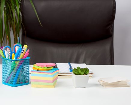 empty brown armchair and white desk with stationery, workplace