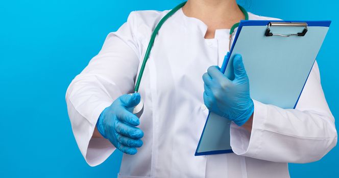 medic woman in white coat, blue latex gloves holding a tablet with a clip for papers, right hand pulls forward for a handshake, blue background