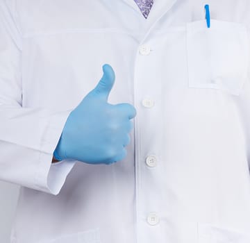 doctor in a white coat and tie shows with his hand a gesture like, wearing blue latex medical gloves, close up