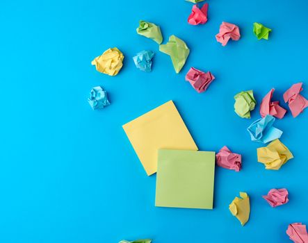multicolored blank paper stickers of different colors on a blue background, copy space