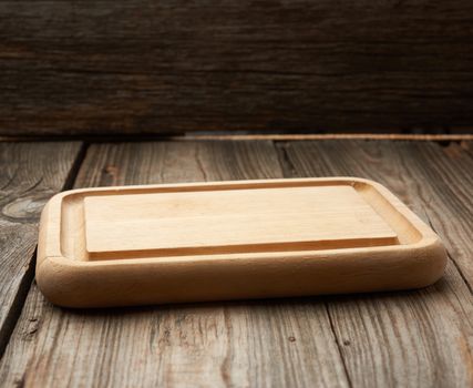 light beige rectangular empty cutting kitchen board on a wooden background from old boards, top view