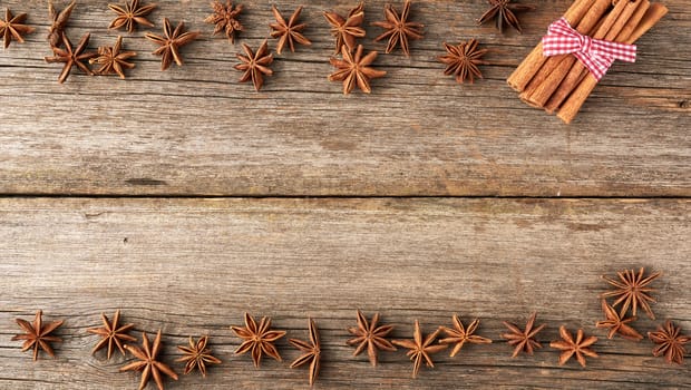 brown cinnamon sticks and dry star anise on a gray wooden background, tasty and fragrant spice, top view, copy space