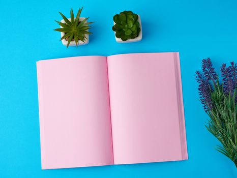 open notebook with blank pink pages, bouquet of lavenders on a blue background, top view, flat lay