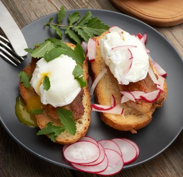 two sandwiches on a toasted white slice of bread with poached eggs, green leaves of arugula and radish in a round plate, top view