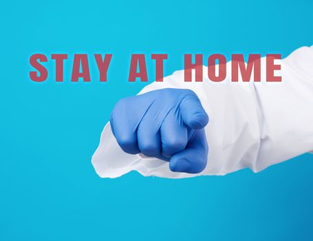 doctor’s hand in a blue sterile glove shows with an index gesture in front, request or appeal to pay attention to stay at home during quarantine