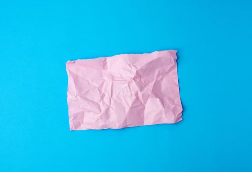 empty crumpled pink rectangular sheet of paper a4 on a blue background, copy space