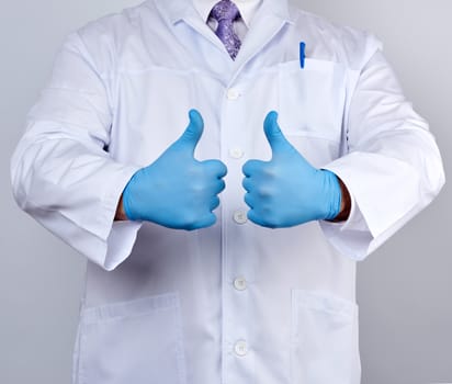 doctor in a white coat and tie shows with his hand a gesture like, wearing blue latex medical gloves, white background