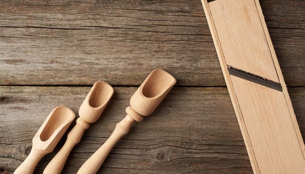 empty wooden spoon and vintage grater for vegetables on a gray wooden background, top view