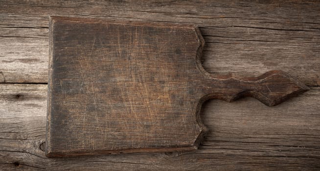 very old empty wooden cutting board, top view, gray wooden background 