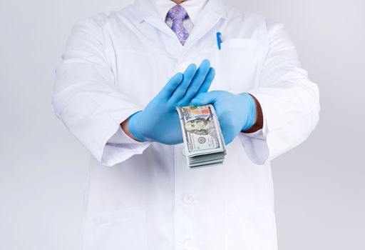 doctor in a white coat and tie, wearing blue sterile gloves, doctor holds a pack of paper money and refuses to take a bribe, anti-corruption concept