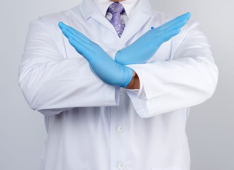 doctor man in a white coat and blue latex gloves crossed his arms in front of his chest, gesture of rejection, denial