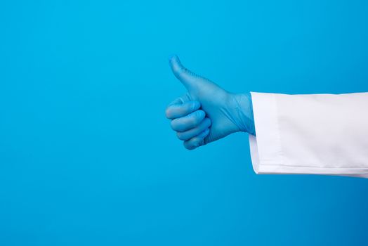 medic woman in white coat, wearing blue medical latex gloves on her hands, showing like gesture in hand, approval concept, copy space