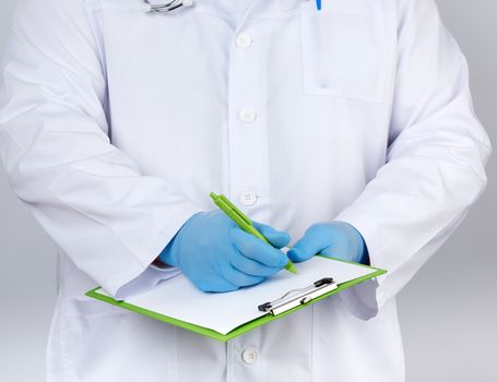 doctor in a white coat and medical blue gloves records a patient’s medical history, close up