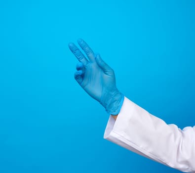 medic in a white coat, blue latex gloves pulls his hand up on a blue background