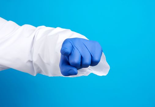 doctor's hand in blue latex glove and white coat, forefinger stretches forward, imitation of pointing pressure, blue background