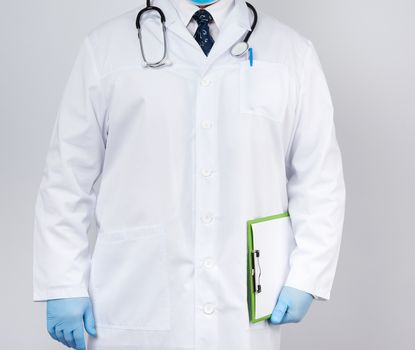 male doctor in a white coat, blue latex gloves, a stethoscope hanging on his neck, doctor holding a green paper holder with a white blank sheet