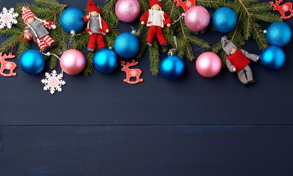 green spruce branches, Christmas blue and pink balls, carved wooden decor on a blue wooden background from boards, copy space