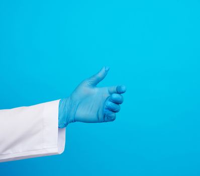 doctor’s hand is wearing a blue sterile rubber glove holding an object, blue background, element for a designer
