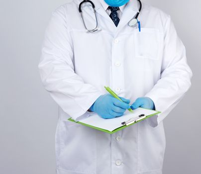 doctor in a white coat and medical blue gloves records a patient’s medical history, close up