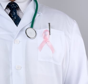 male doctor in a white coat and tie stands and holds a pink silk ribbon in the form of a loop, symbol of the fight against breast cancer in October 