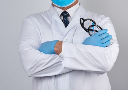 adult male doctor in a white medical coat stands and holds a black stethoscope on a white background
