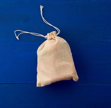 small full brown canvas bag with ties, blue wooden background, top view. Reusable eco bag. 