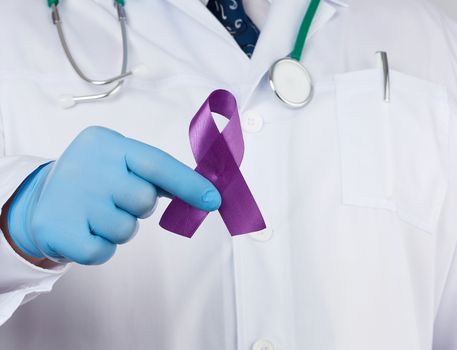male doctor in a white coat and tie stands and holds a purple silk ribbon in the form of a loop, wearing blue sterile medical gloves. Symbol of early research and disease control, Alzheimer's disease