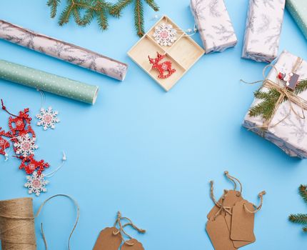 roll of wrapping paper, decor, spruce branches, Christmas toys and boxes with gifts on a blue background, top view. Christmas holiday concept