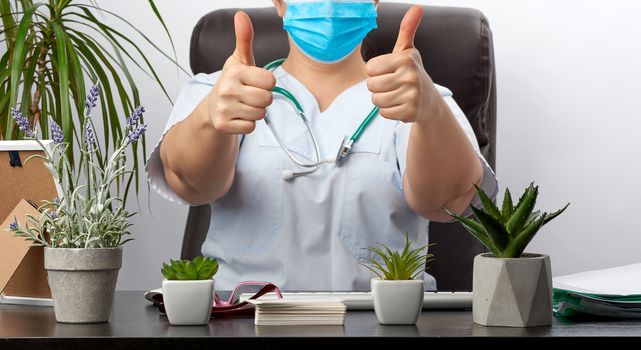 medic woman in white uniform showing like gesture in hand, approval concept, close up, therapist sits at a black table in the office