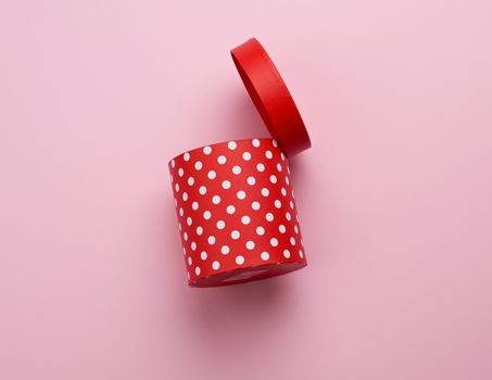 empty round red cardboard box in white polka dots on a pink background, holiday backdrop