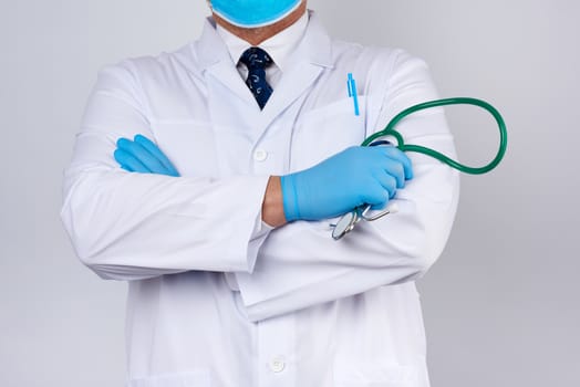 adult male doctor in a white medical coat stands and holds a green stethoscope on a white background