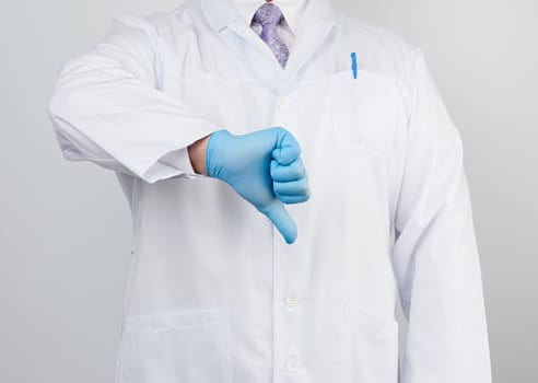 doctor in a white coat with buttons shows a gesture of dislike with his hand, wearing blue medical glove, emotion of negativity
