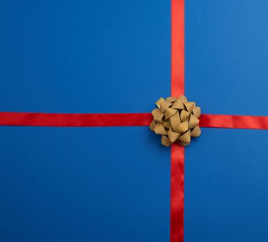 blue silk ribbon crossed on a dark blue background in the middle of a golden bow, imitation of tying a gift, top view