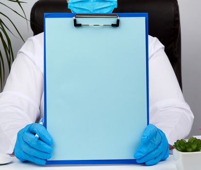 female doctor's hands in blue medical latex gloves holds a folder with a paper clip, place for writing a diagnosis, message