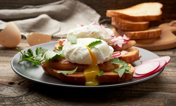  sandwiches on a toasted white slice of bread with poached eggs, green leaves of arugula and radish in a round plate, morning breakfast