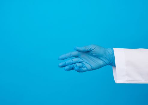 medic in a white coat, blue latex gloves pulls his hand for a handshake on a blue background