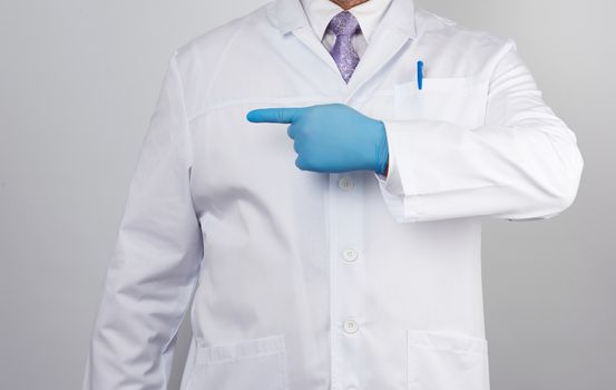 medic man in white coat with buttons,  on  hands wearing blue sterile gloves, showing hand gesture indicating the subject, white background